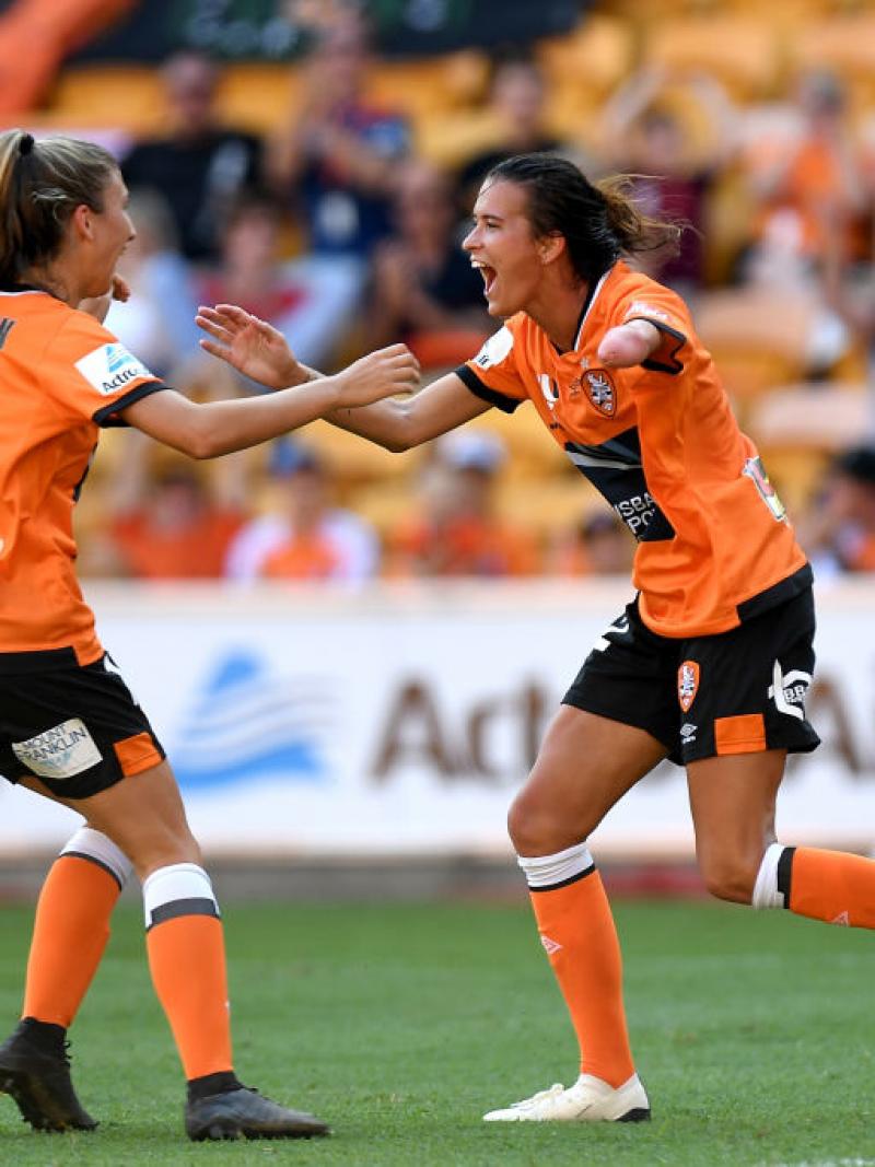 A woman who is missing her left forearm runs towards a teammate in celebration.
