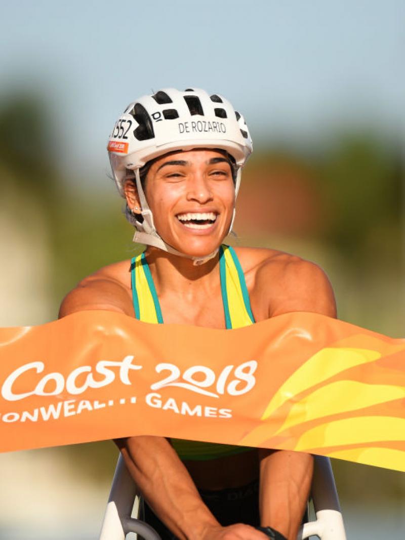 A female wheelchair racer crossing a finish line and smiling