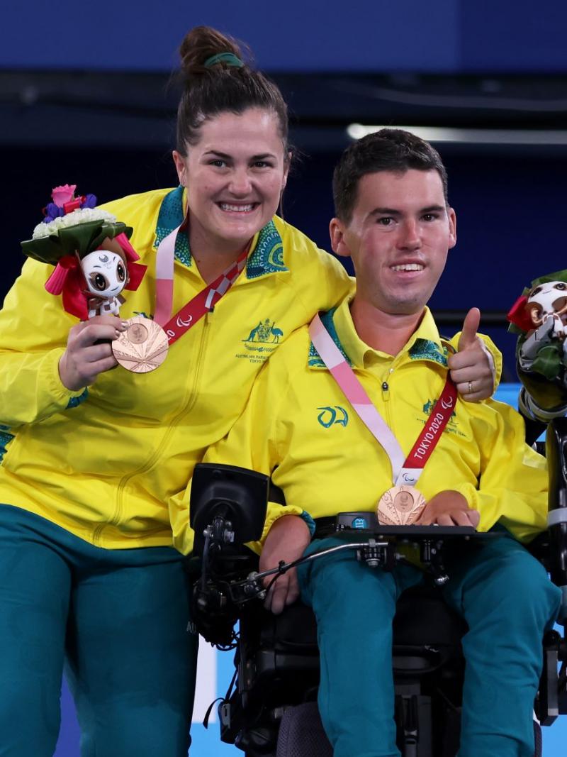 Australian boccia player Daniel Michel and ramp assistant Ashlee McClure smile on the podium after winning bronze at the Tokyo 2020 Paralympic Games.
