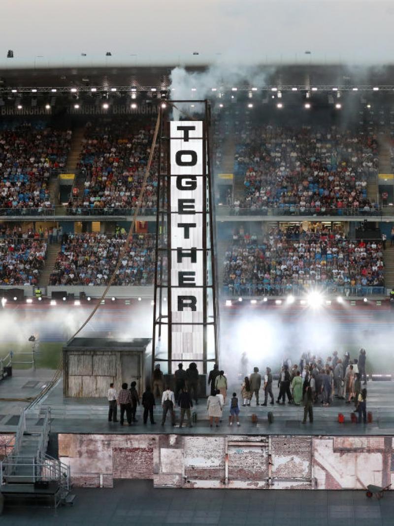 A banner reads 'Together' as post-war Birmingham is recreated onstage during the 2022 Commonwealth Games Closing Ceremony.