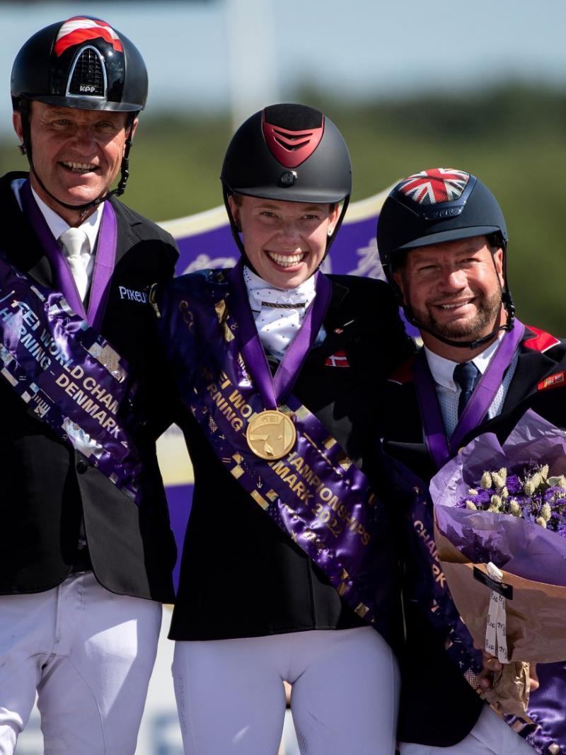 Three athletes smile after receiving their medals at the Para Dressage World Championships.