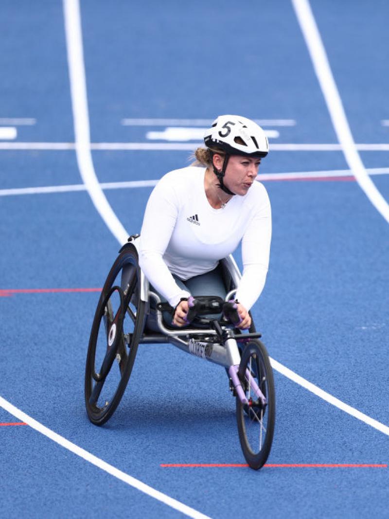 A female wheelchair racer after crossing the line in a blue track
