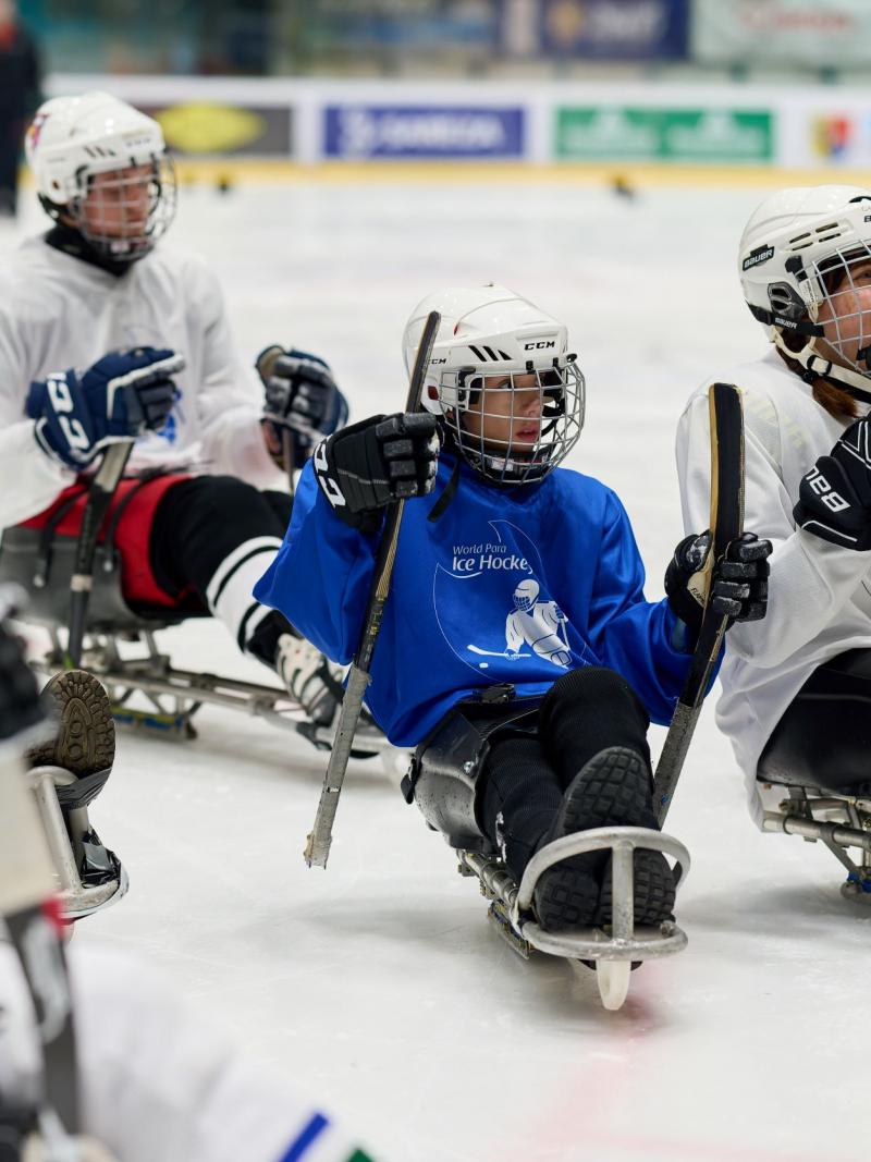 Para ice hockey players hold sticks on the ice.