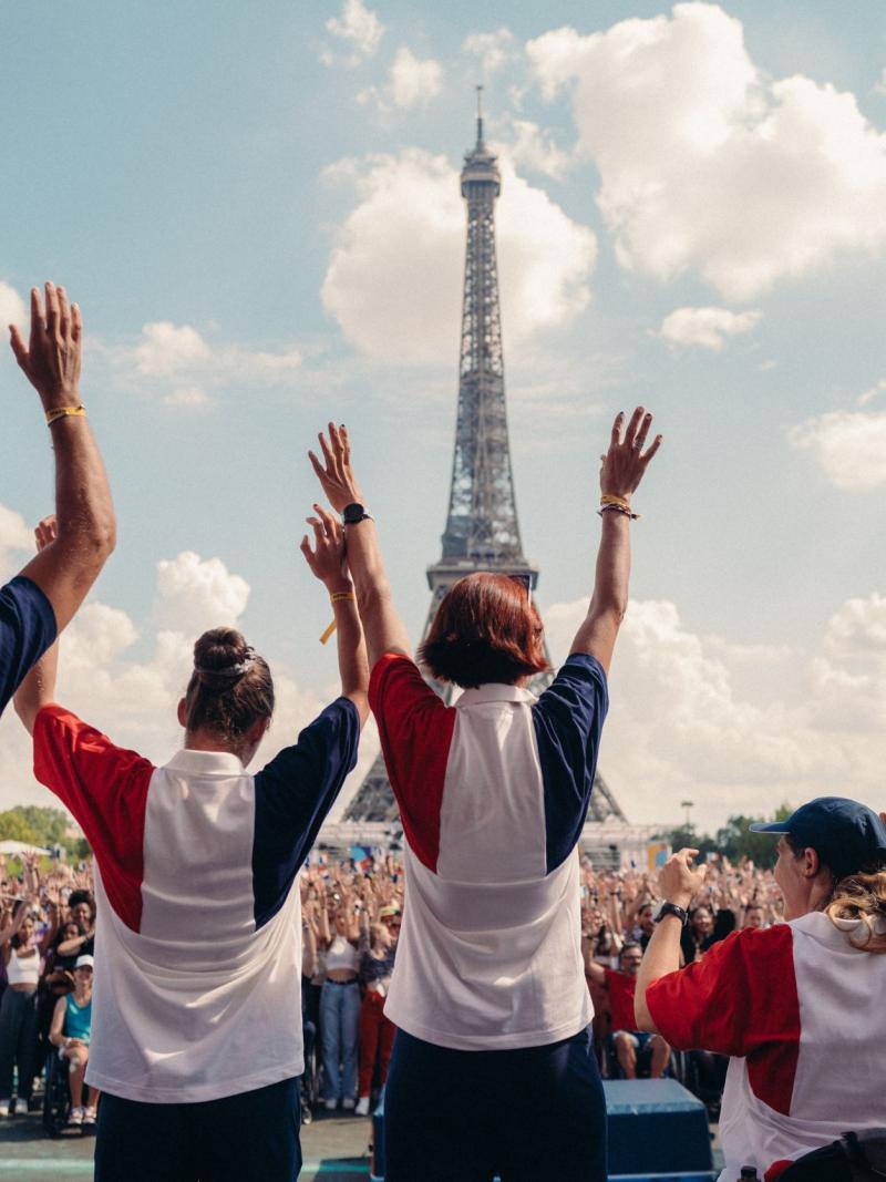 People wearing the colours of the French flag wave in front of the Eiffel tower in Paris.