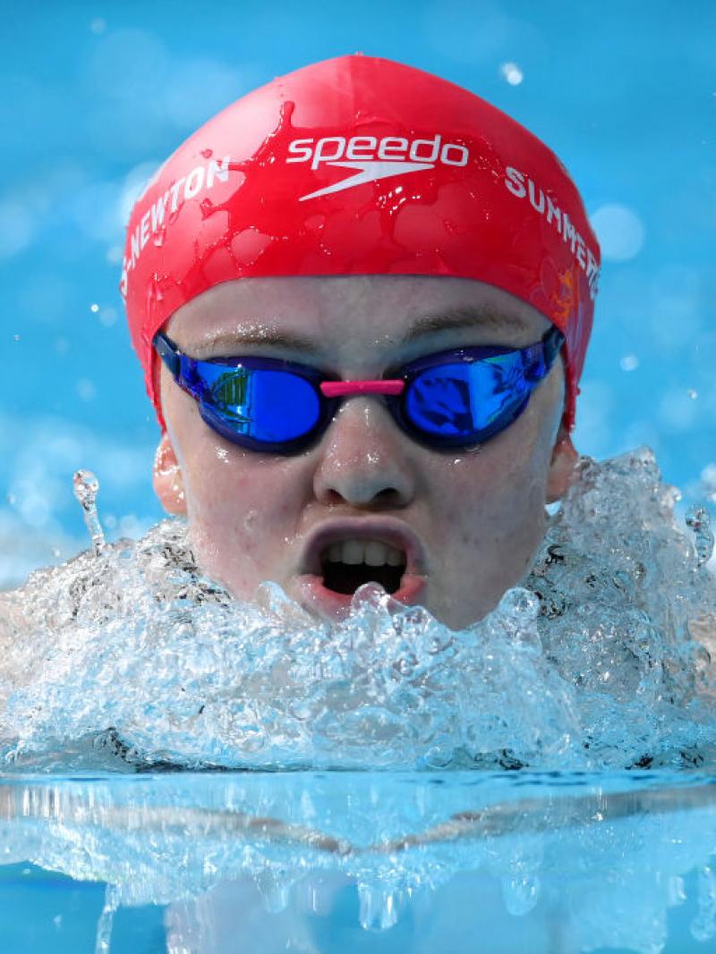 A close up of a female swimmer as she comes up for a breath during a breaststroke race.