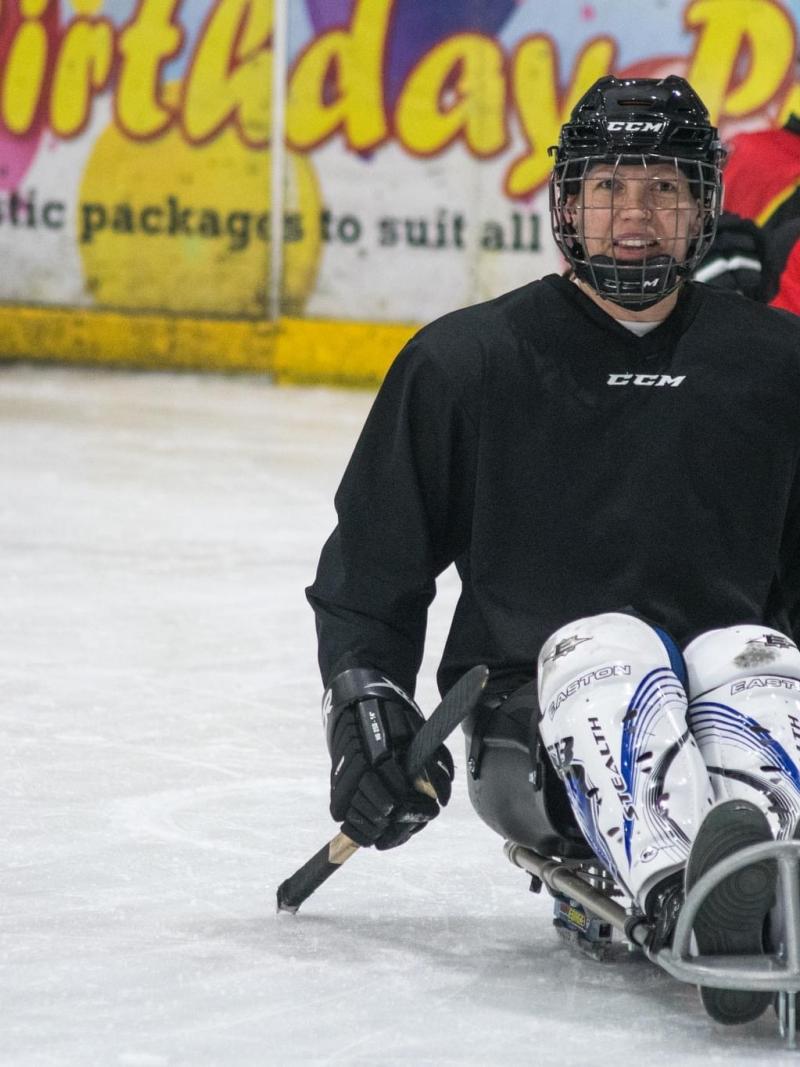A group of four female Para ice hockey players on an ice rink
