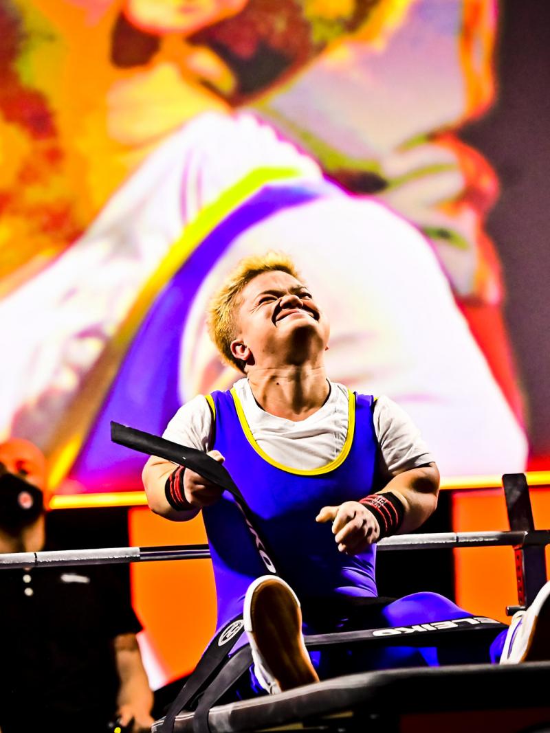 A female Para powerlifter takes off her belt and celebrates after a lift.