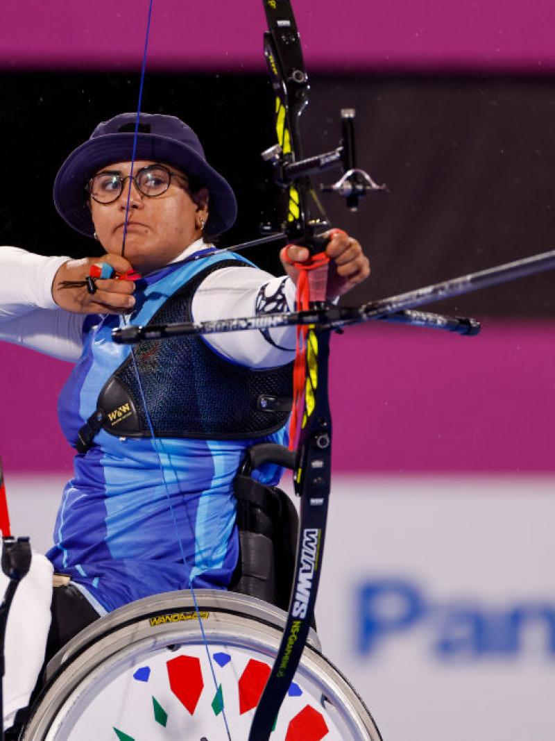 A female athlete on a wheelchair is pulling a bow at the Tokyo 2020 Paralympic Games.