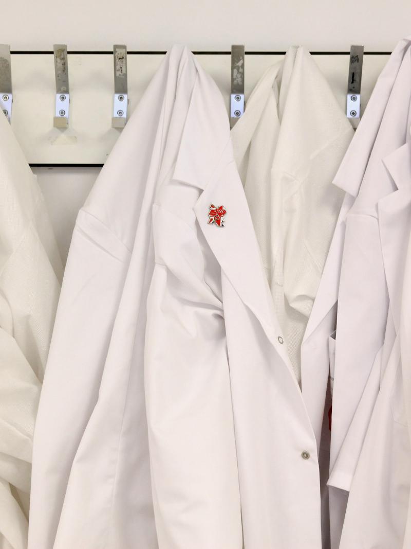 White lab coats hang on the wall in an anti-doping laboratory.