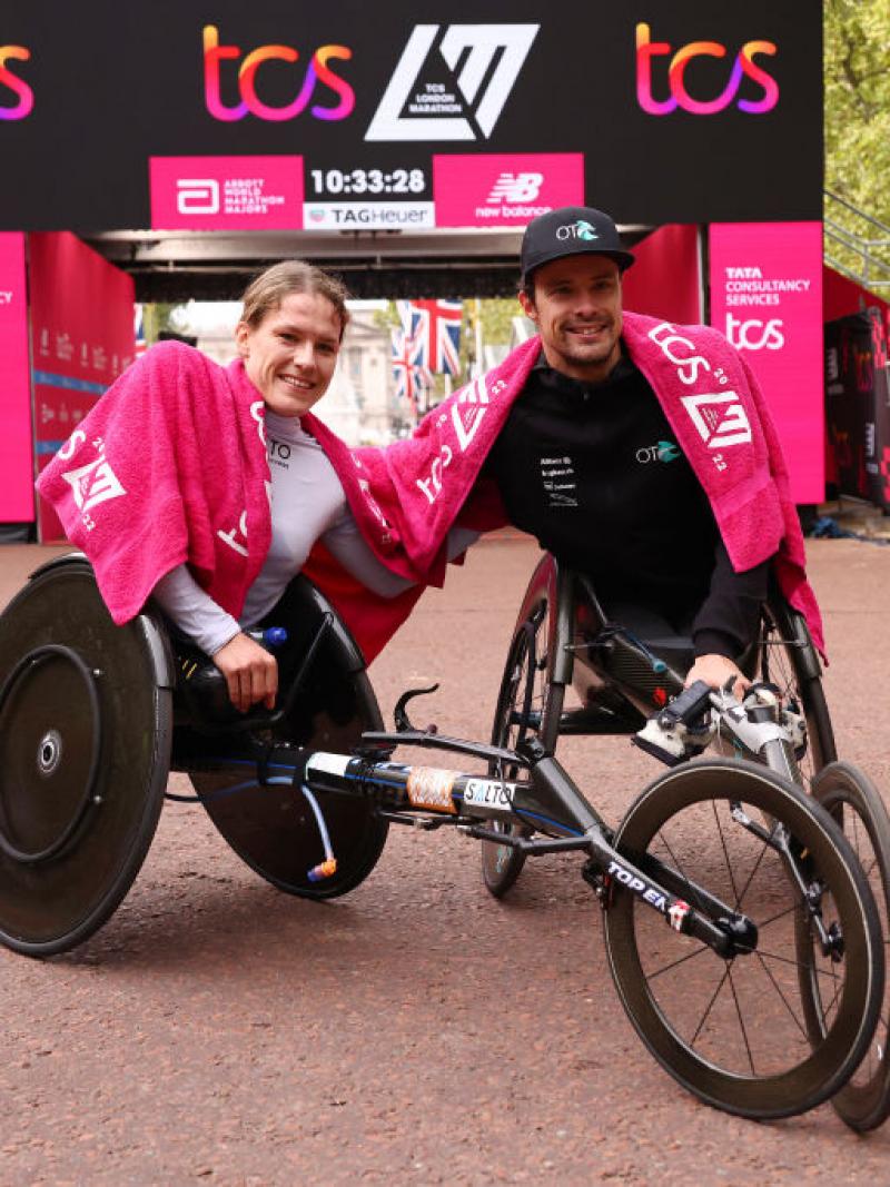 A woman and a man in racing wheelchair racers in front of the finish line of the London Marathon