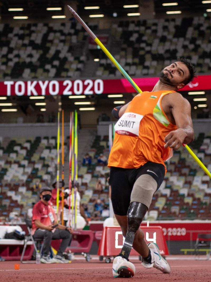 A male athlete with a prosthetic leg steps forward to throw a javelin