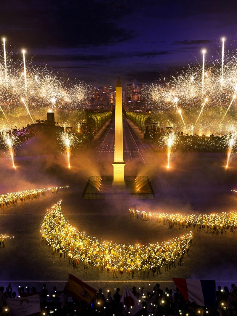A mock-up image of a pyro show in which people standing in the formation of an Agitos sign hold up lights in the Place de la Concorde.