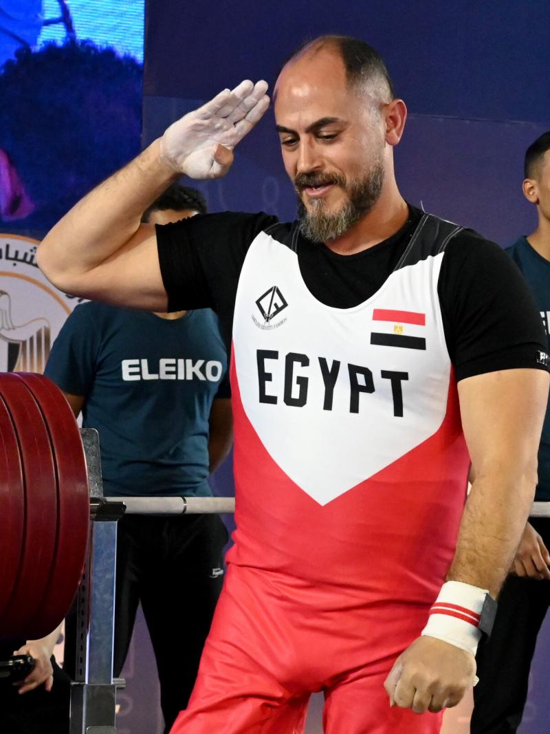 A man salutes with his right arm after lifting weights on a bench press.