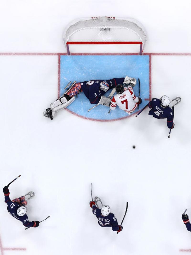 An aerial view of a Para ice hockey game with five players on ice