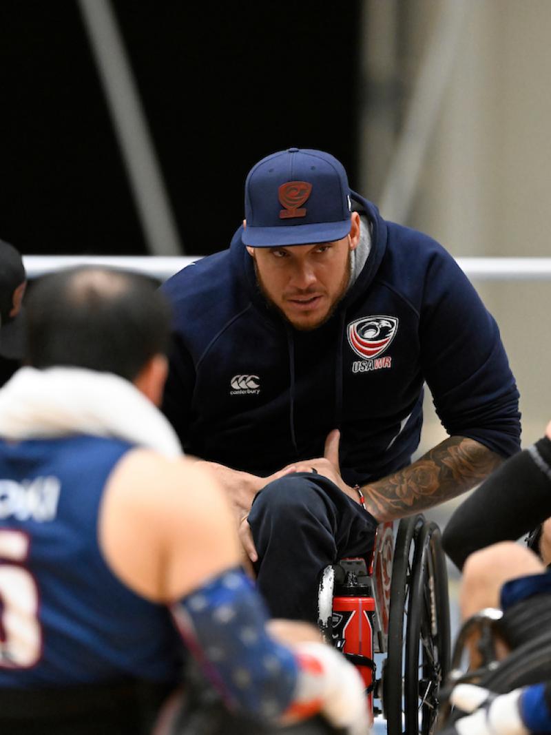 A man using a wheelchair speaks to wheelchair rugby players