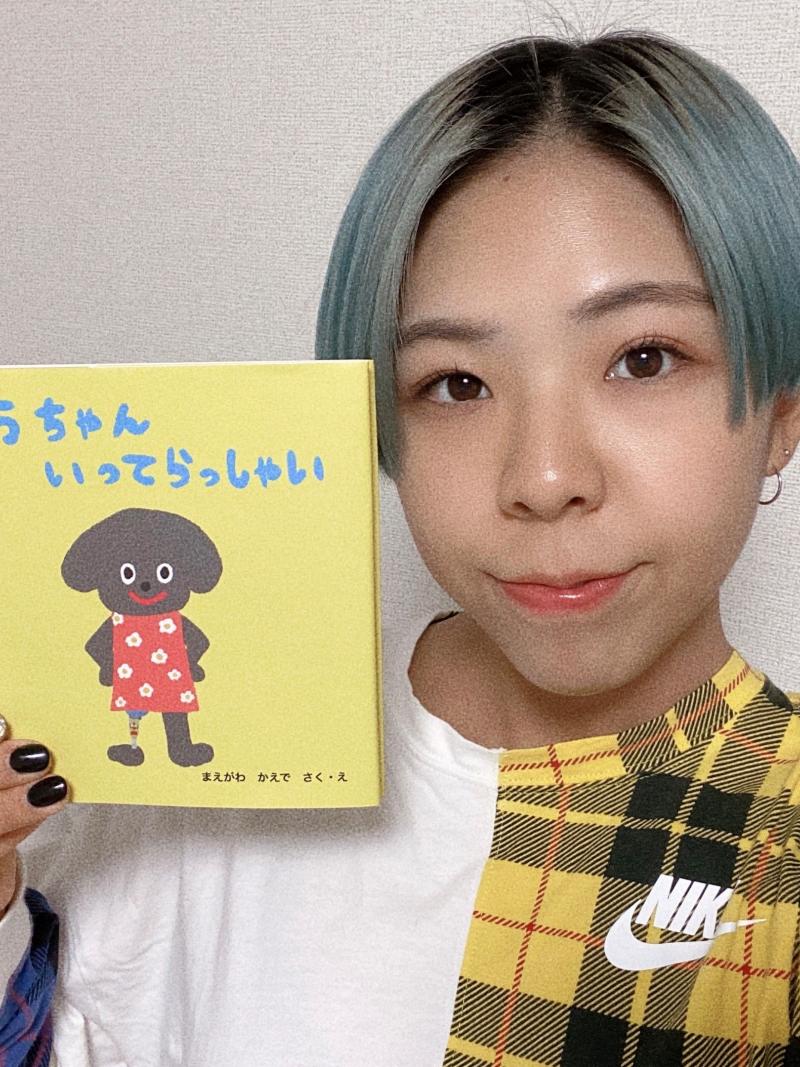 A female athlete holds a yellow picture book about a dog with a prosthetic leg