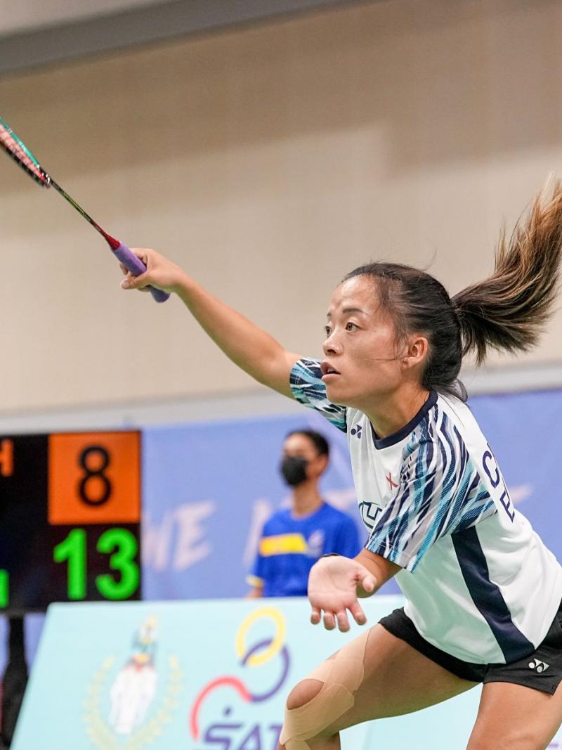 A female athlete plays badminton during a match.