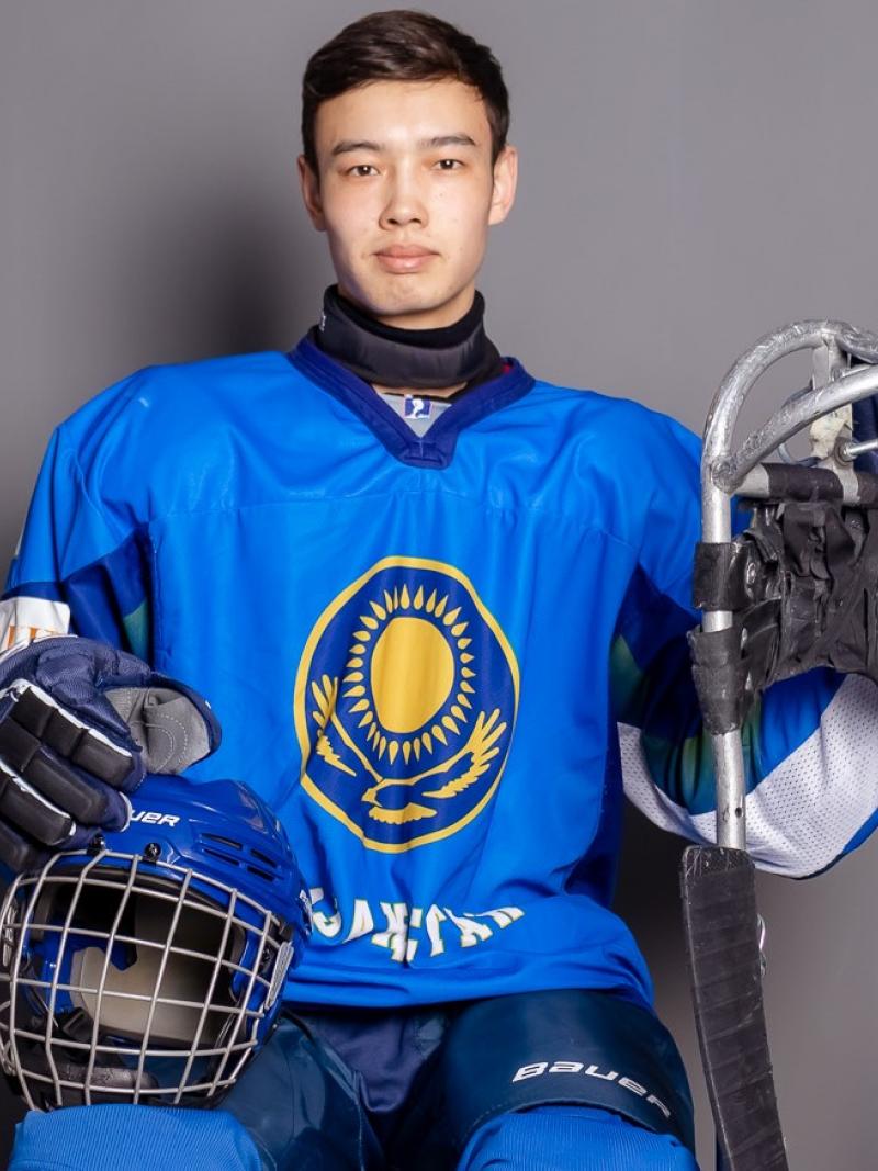 A man posing for a picture with Para ice hockey equipment