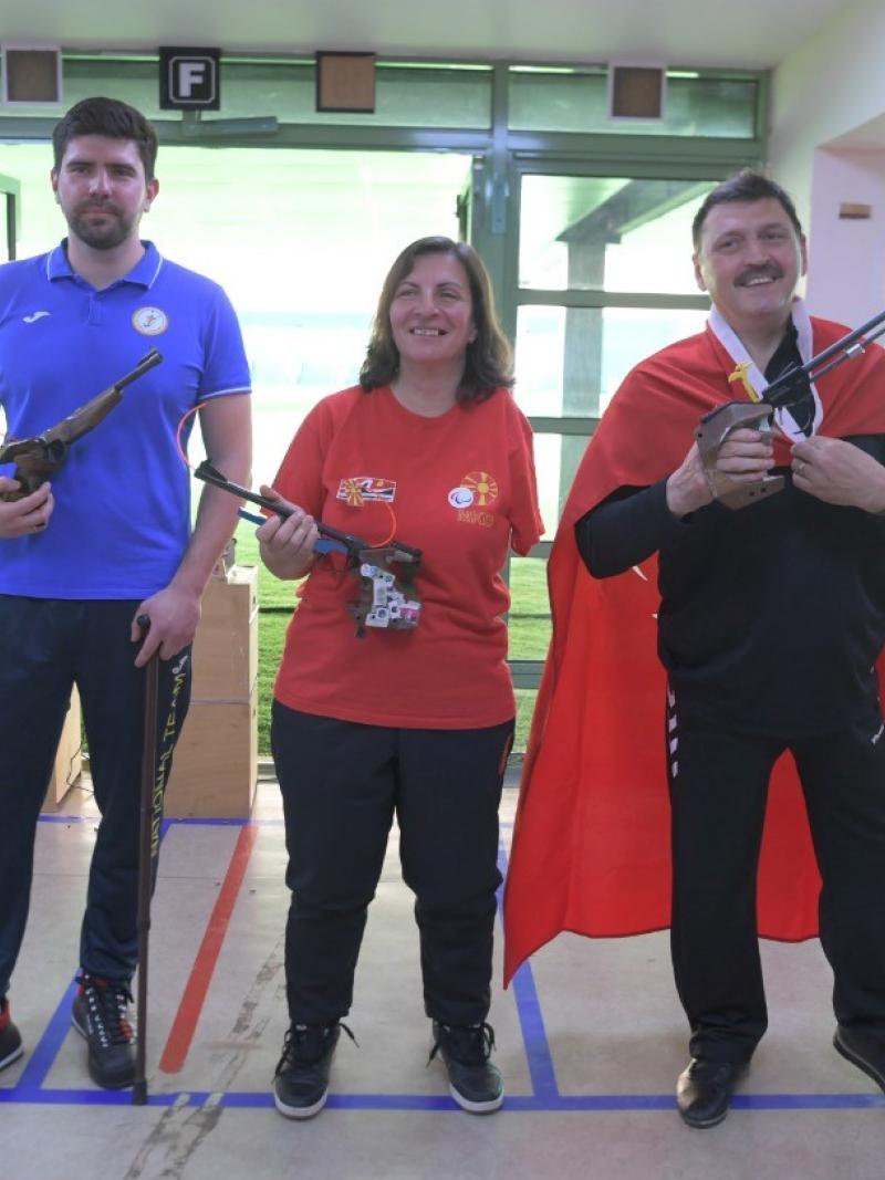 A woman standing between two men in a shooting range