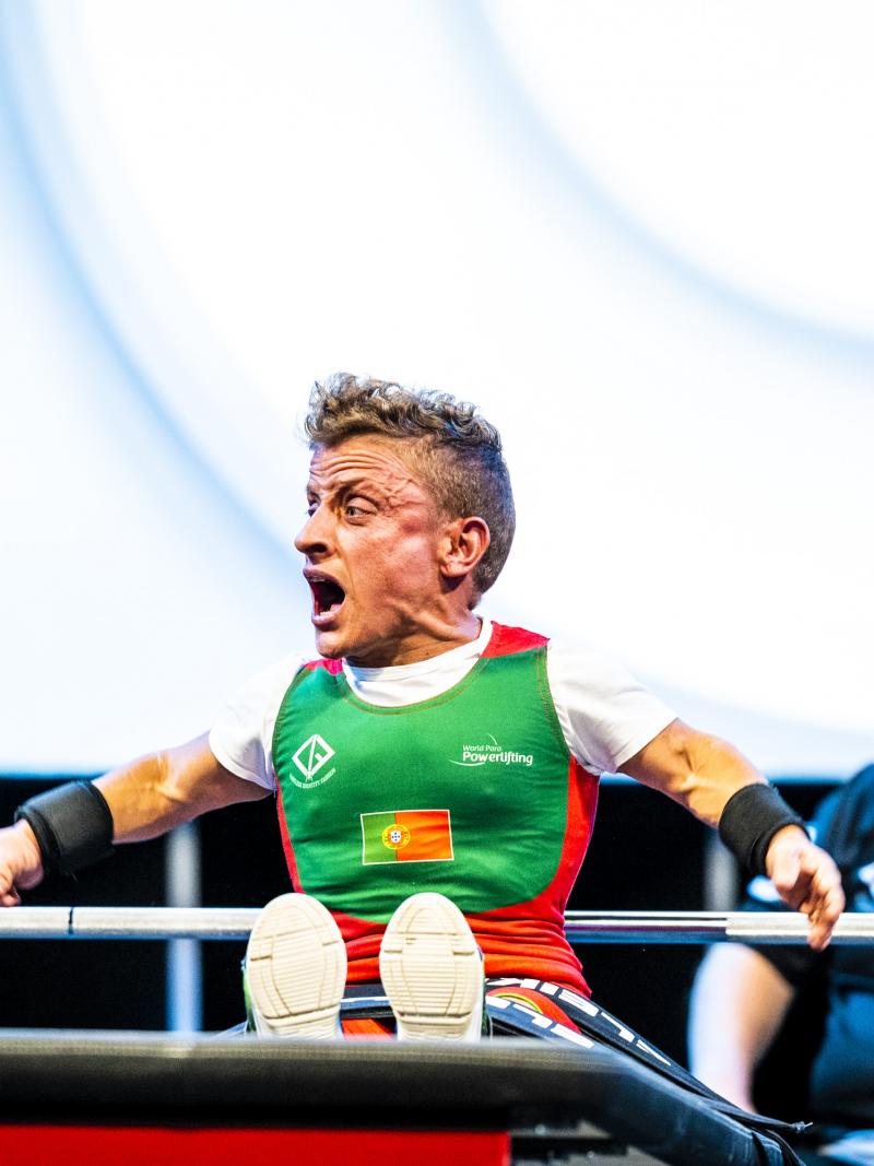 A female Para powerlifter celebrates with a cheer on the bench after a successful lift.