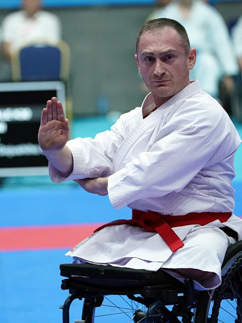 A male athlete wearing a white karate uniform performs during a competition