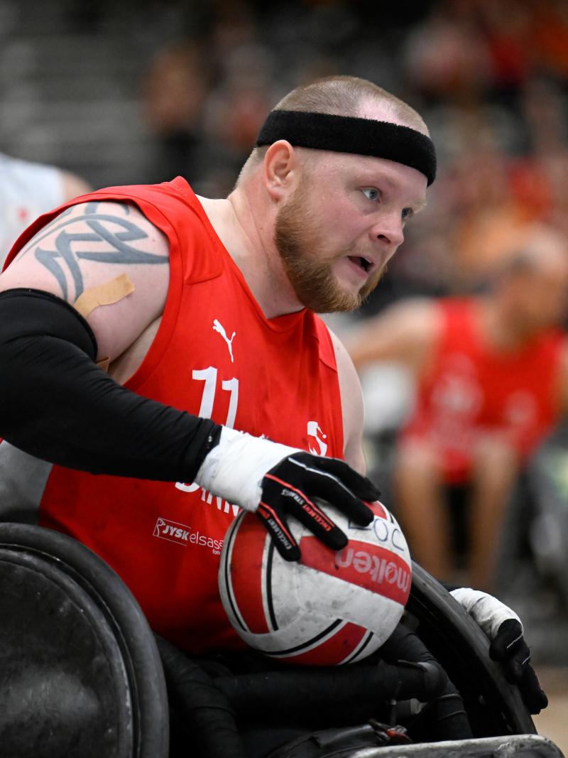 A male wheelchair rugby player carries the ball during a game