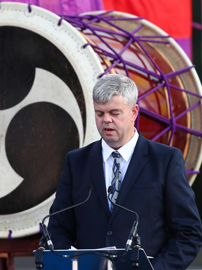 A man in a suit with a vision impairment speaks at a podium on a stage.