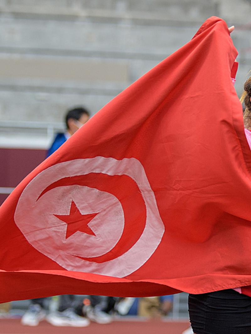 A short-stature woman celebrating with the flag of Tunisia