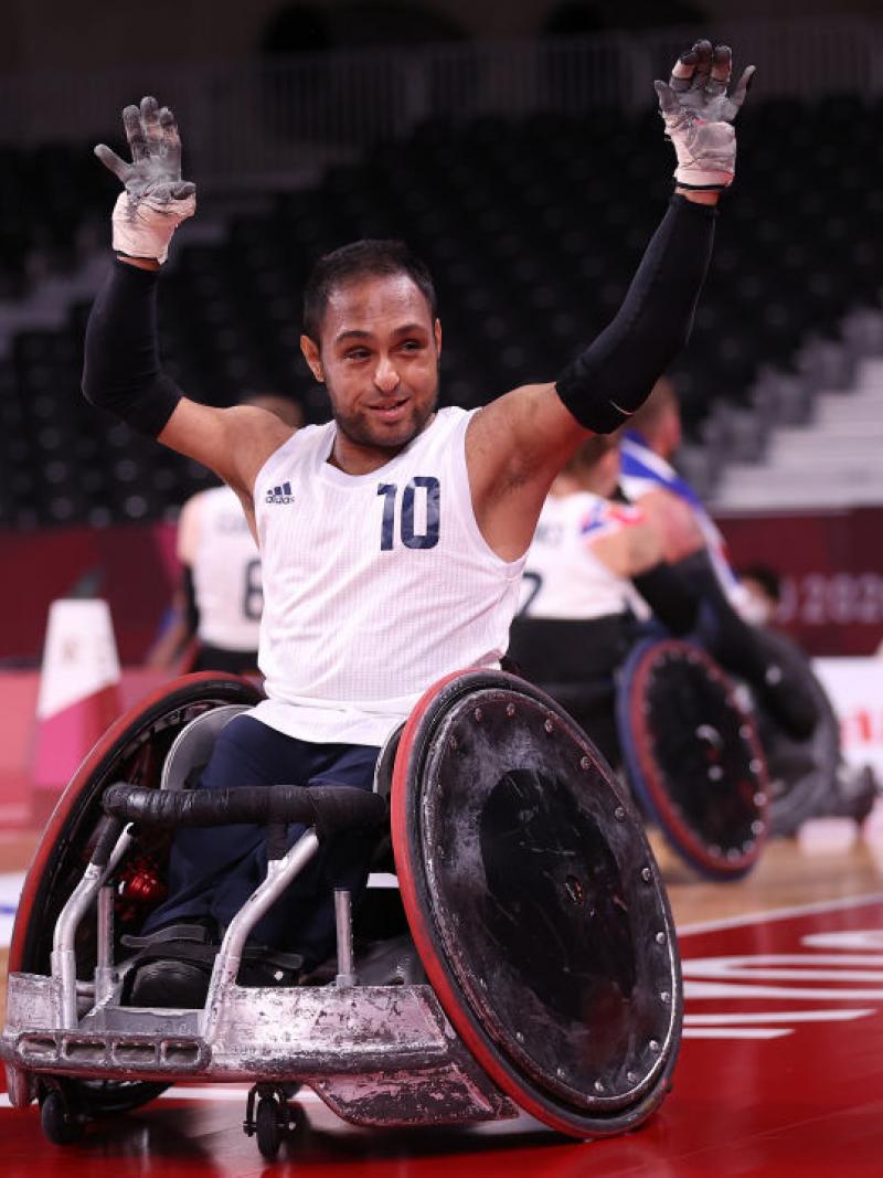 A male wheelchair rugby player raises both hands in celebration at the Tokyo 2020 Paralympic Games.