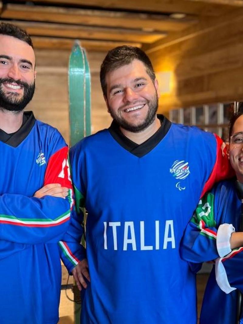 Three men wearing Italy's Para ice hockey jersey posing for a picture