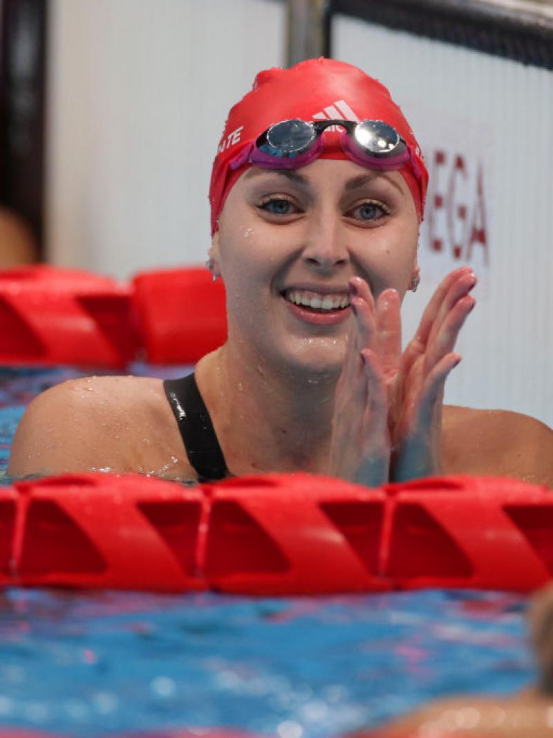 A female Para swimmer claps her hands in the pool after finishing her race.