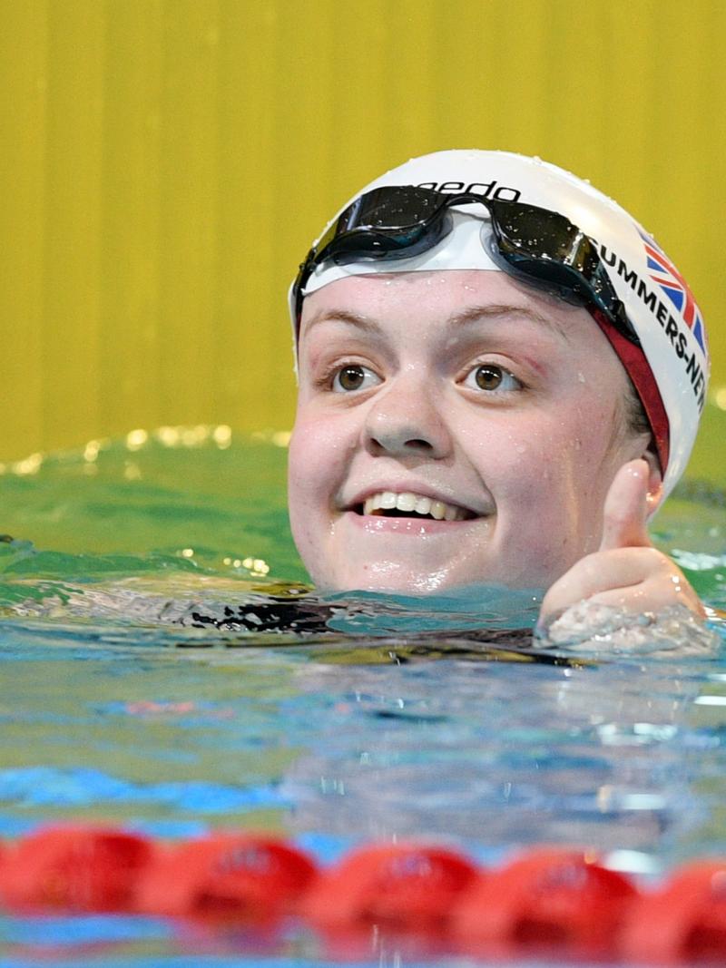 A female swimmer smiling from inside the pool