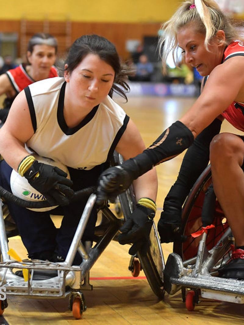 Two female wheelchair rugby players compete