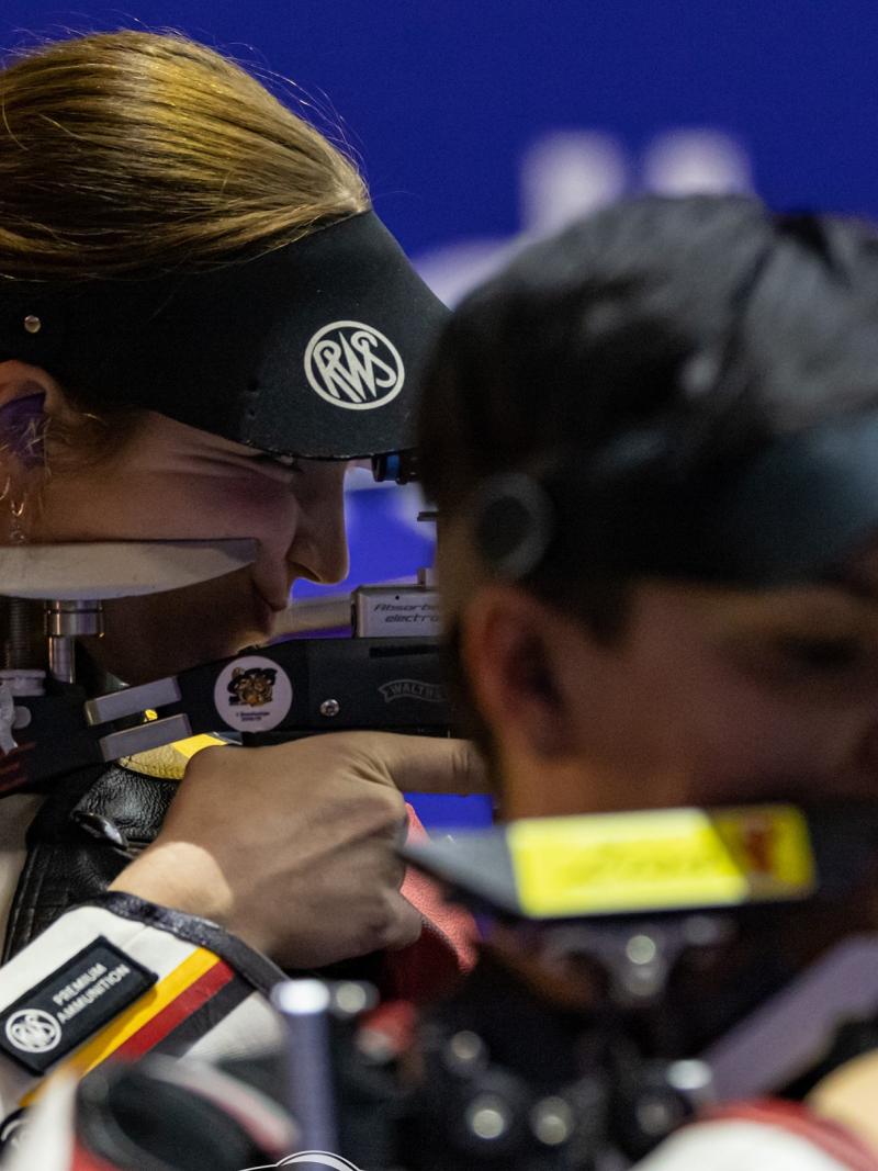 Three women competing in rifle shooting Para sport event indoors