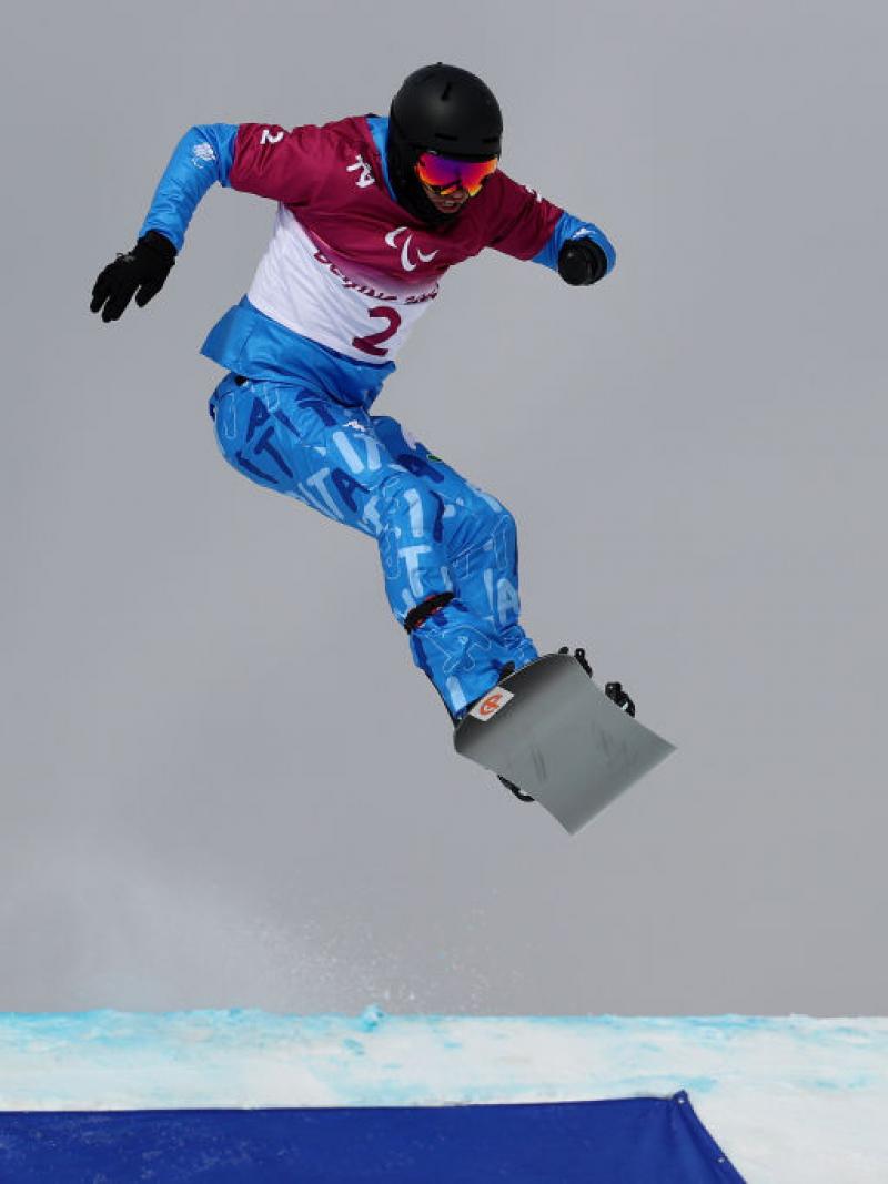 A male snowboarder jumps during his race.