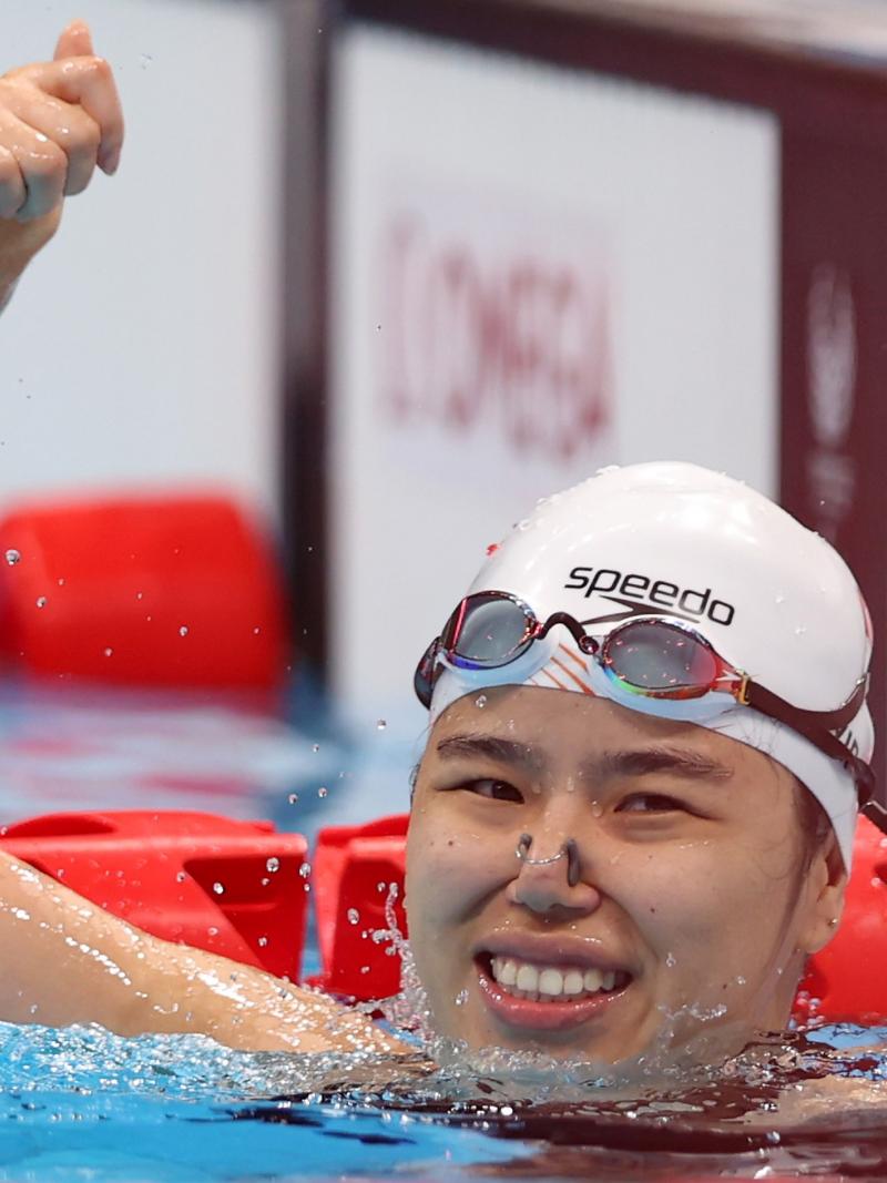 A female swimmer waving from inside the pool