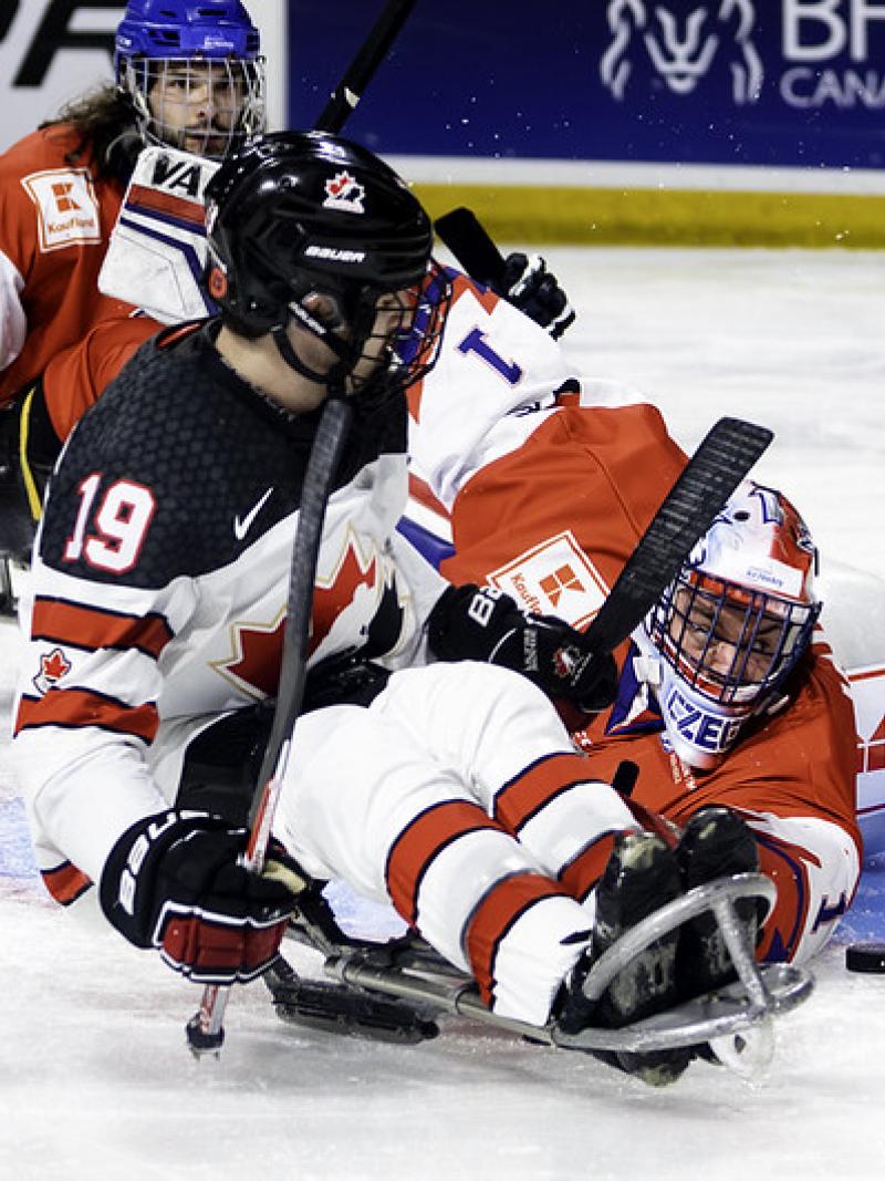 A Para ice hockey player trying to score in front of the goaltender