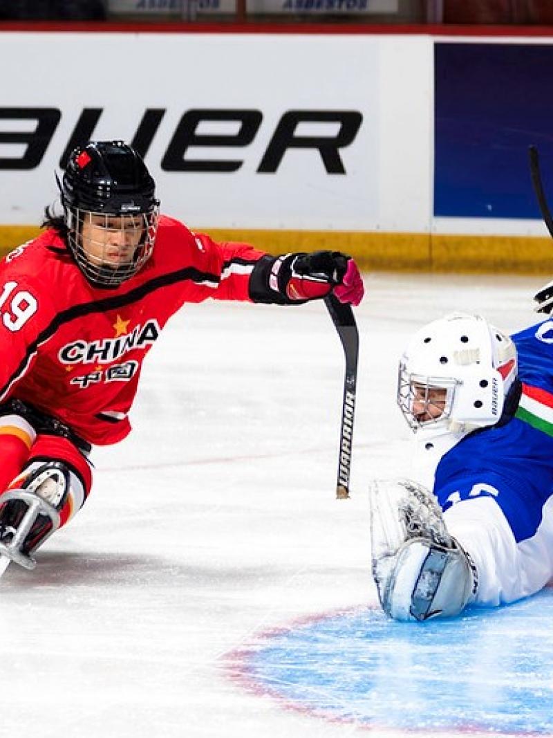 A  Para ice hockey player taking a shot in front of a goaltender