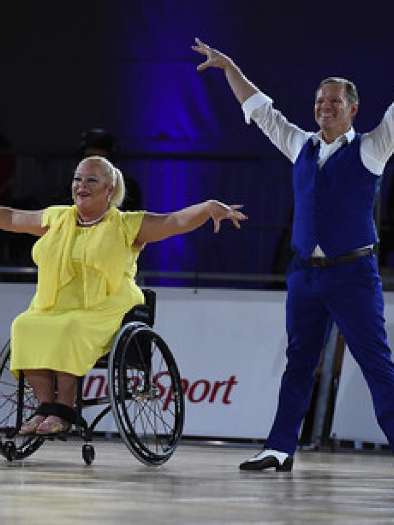 A female wheelchair dancer next to her standing male dance partner