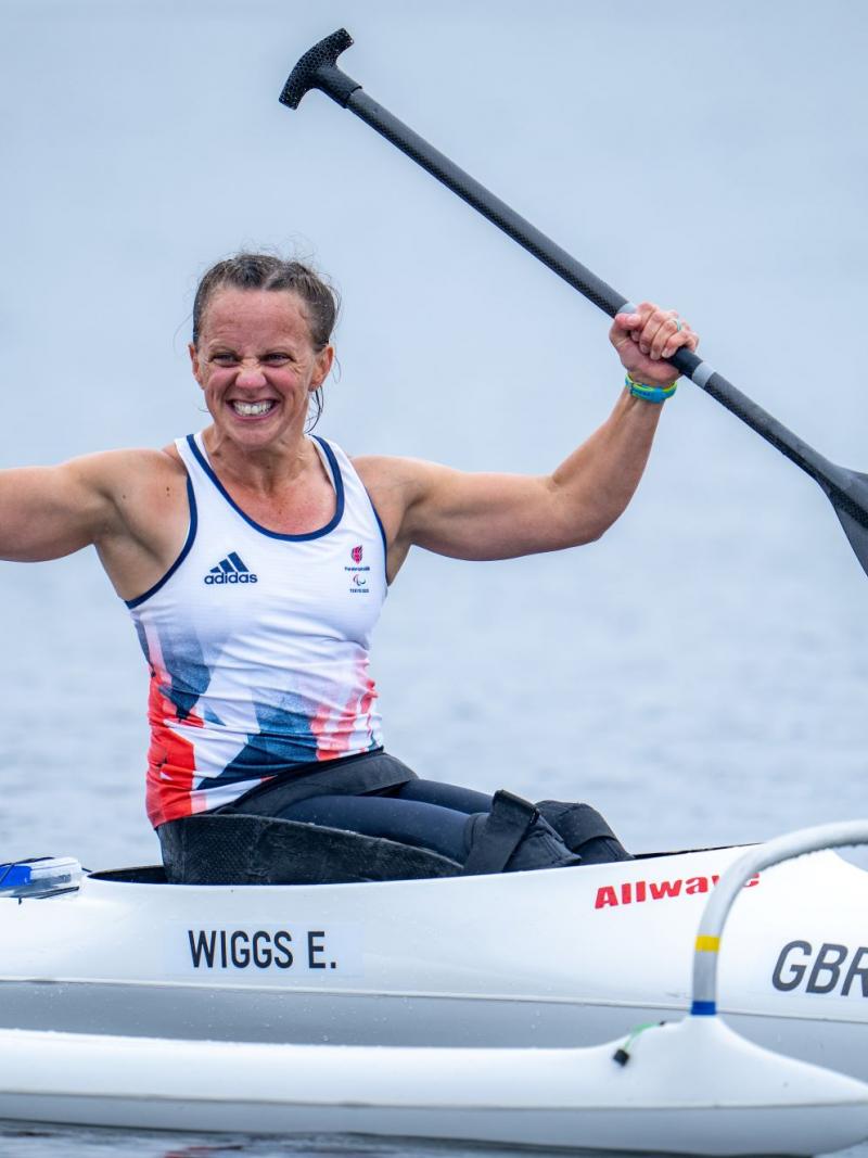 A female Para canoe athlete celebrates on her boat after winning her race at Tokyo 2020.