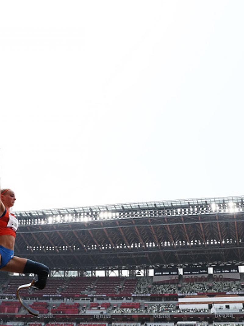 A female athlete with prosthetic legs jumping in an empty stadium