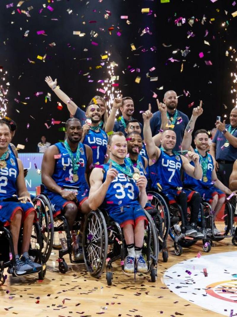 About 20 wheelchair basketball players and officials celebrate after winning the gold medal.