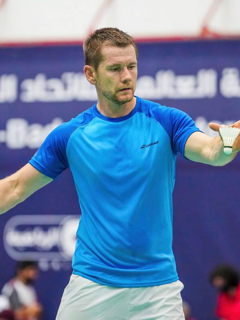A male athlete serving in a badminton match