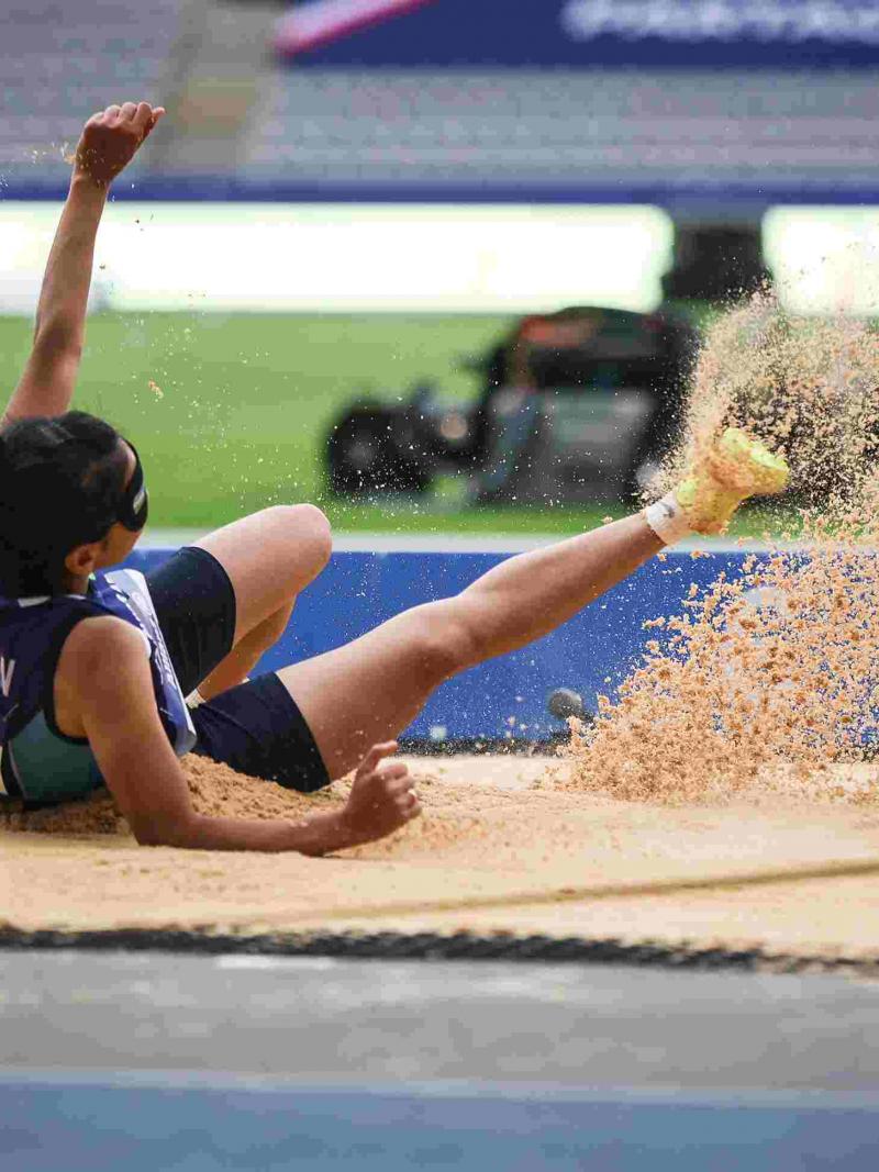 A female long jumper landing on a sand box