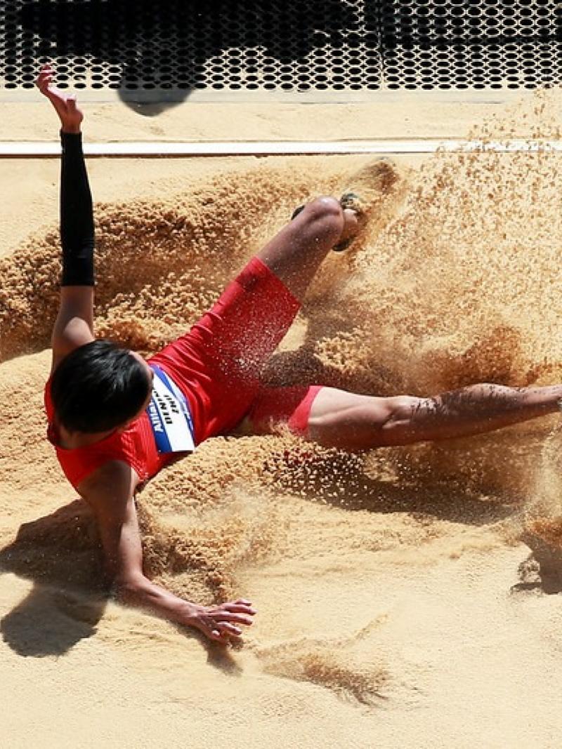 A man landing in the sand pit in a long jump event