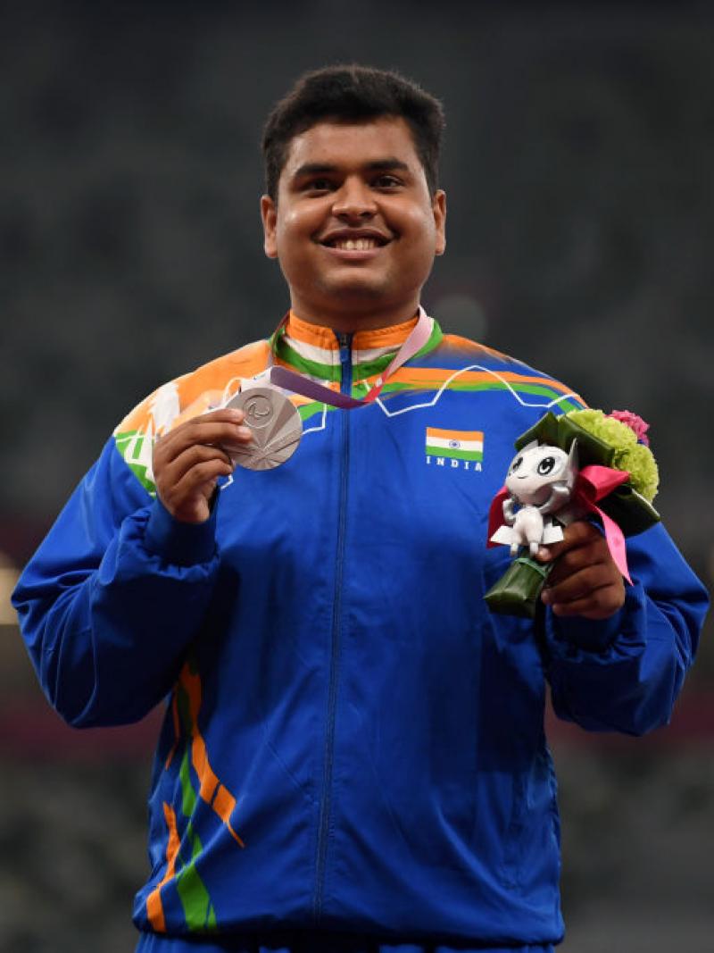 Yogesh Kathuniya smiling and holding up a Paralympic silver medal