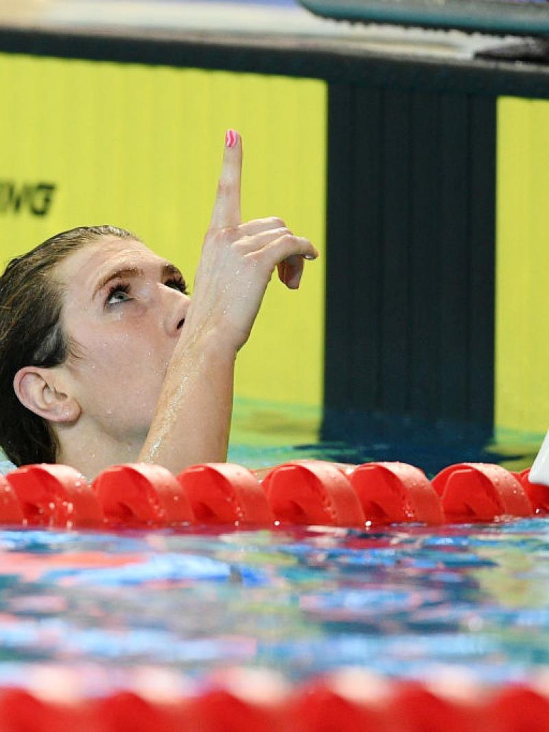 A female swimmer in the water pointing to the sky