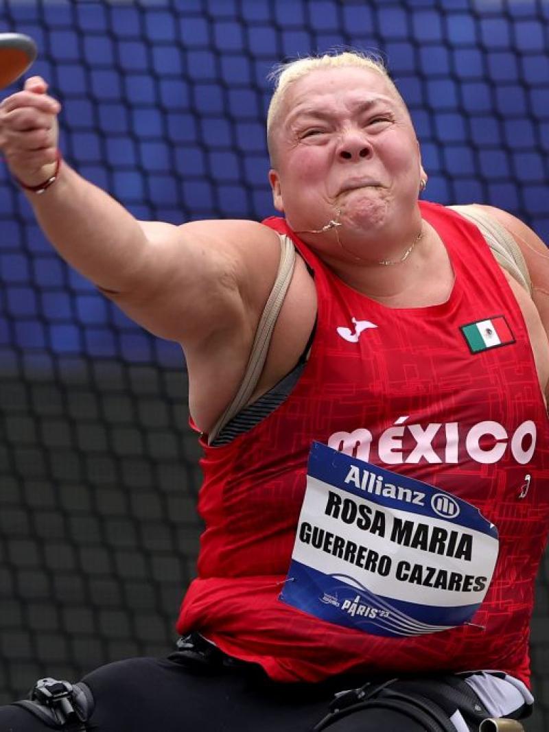 A female seated athlete throws a discus 