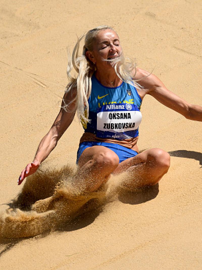 A female long jumper landing on the sand box