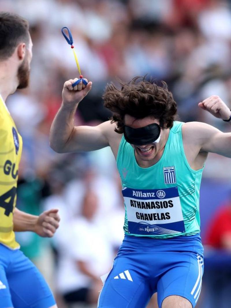 A blindfolded athlete celebrating near an athlete with a guide bib